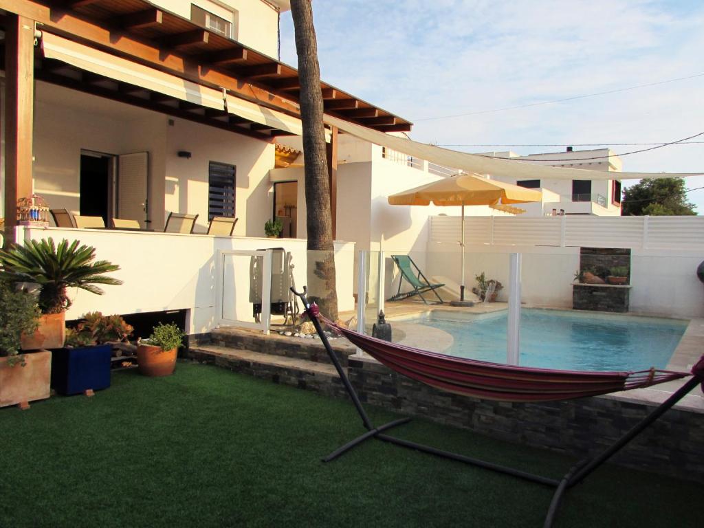 a hammock in the yard of a house with a swimming pool at VIILA ROMPEOLAS JUNTO al MAR con PISCINA PRIVADA in Vera
