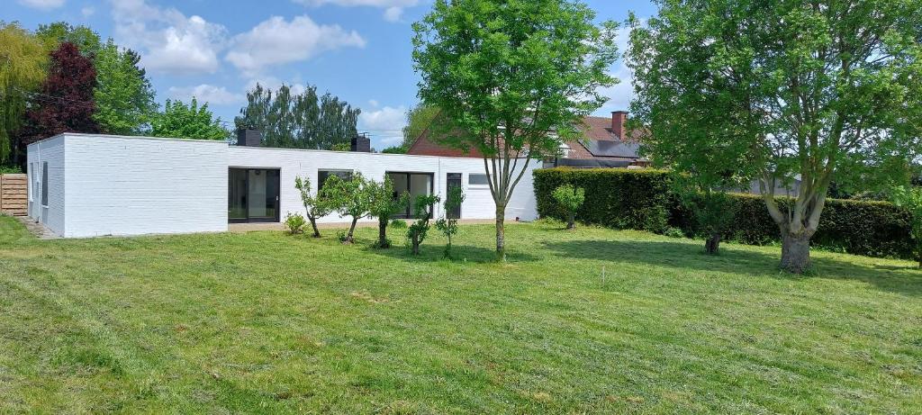 una casa blanca con árboles en un patio en Villa Del, en Moorslede