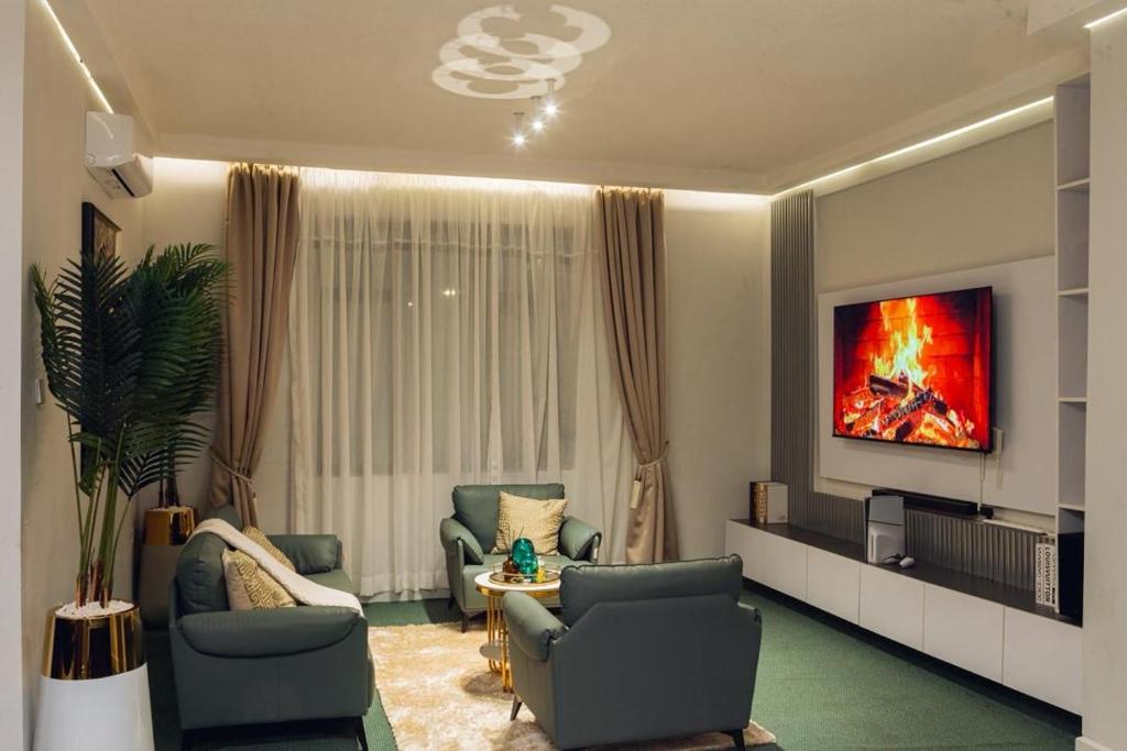 a living room with two chairs and a tv at INEZA SUITEs in Kampala