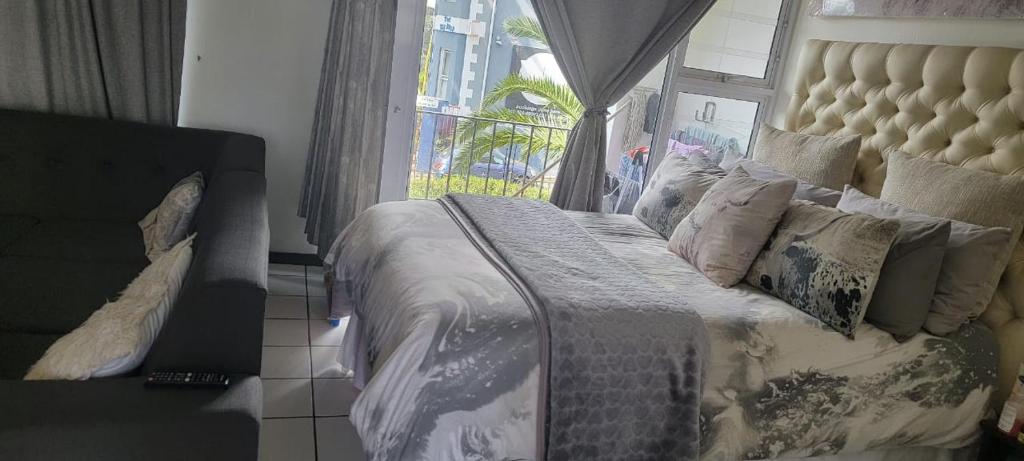 1 dormitorio con 1 cama grande con almohadas y ventana en Cascades apartments, en Ciudad del Cabo