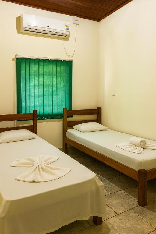 two beds in a room with a green window at Hotel Brisa do Araguaia SFA in São Félix