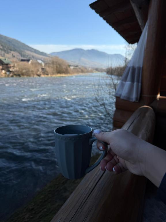 a person holding a coffee cup on a balcony at Над рікою Міжгірʼя in Mizhhirʼʼya