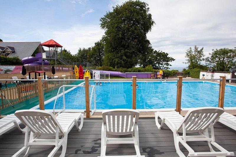 a deck with two chairs and a swimming pool at 23 Sea Valley, Quiet Chalet at Bideford Bay holiday park in Bideford