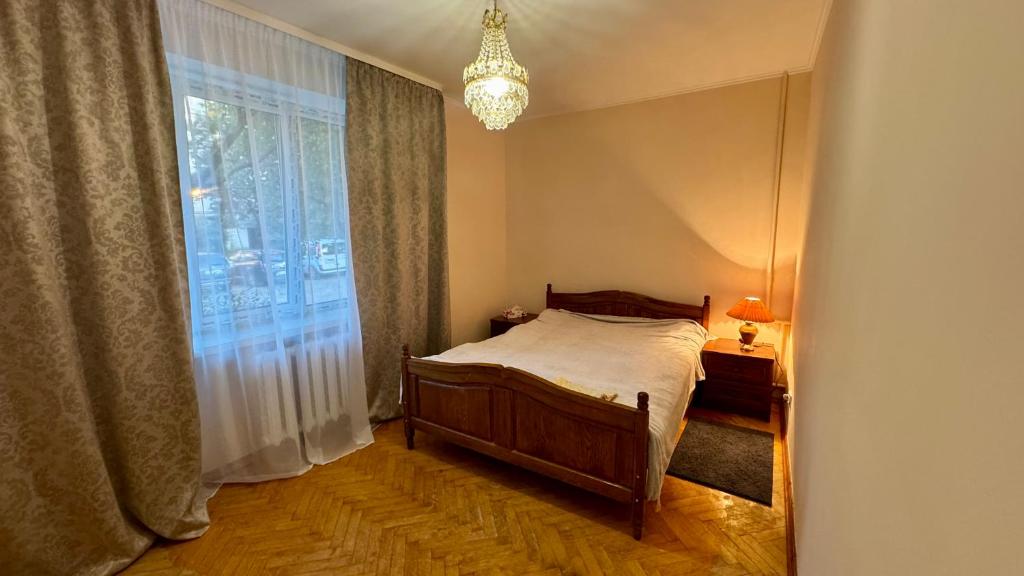a bedroom with a bed and a window with a chandelier at Апартаменти в центрі міста in Luts'k