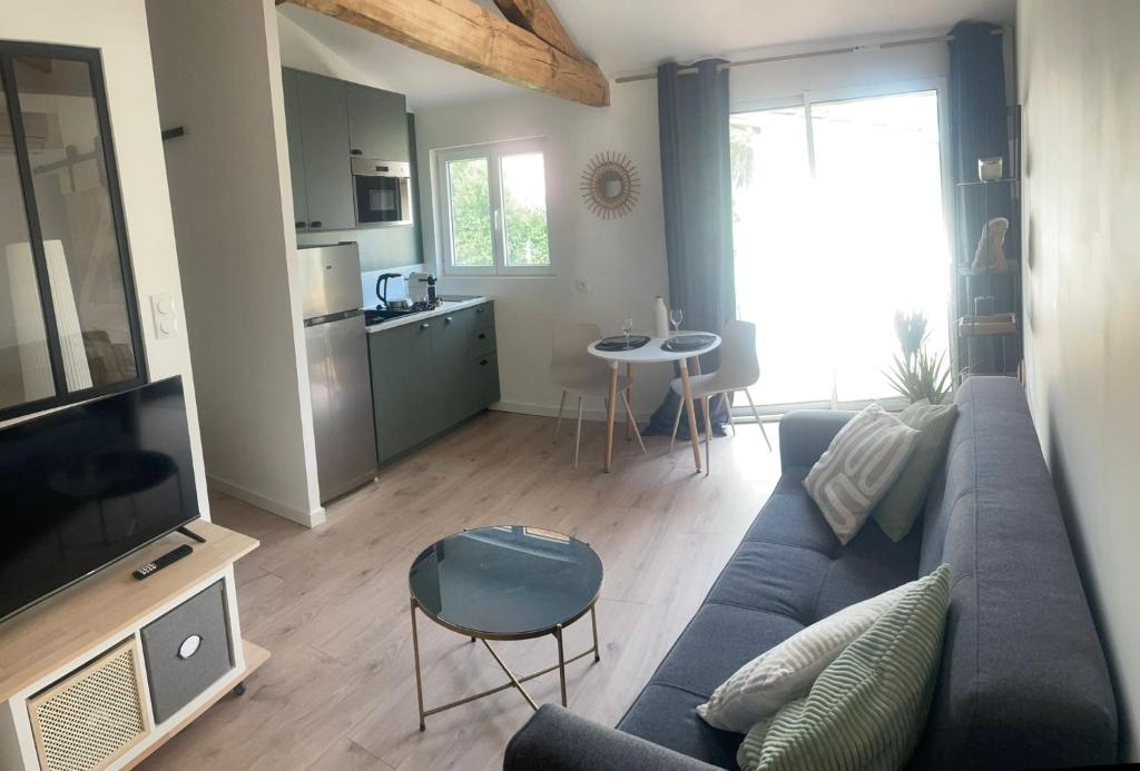 ミミザンにあるEntre bourg et plage, climatisé, grande terrasse, WIFI, parking gratuit, linge et ménage comprisの青いソファとキッチンのあるリビングルーム