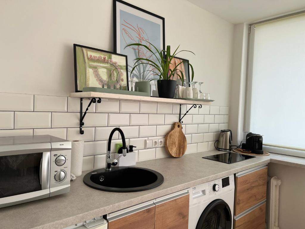 a kitchen with a sink and a microwave at DvaroStudio jaukus butas centre self-check-in in Šiauliai