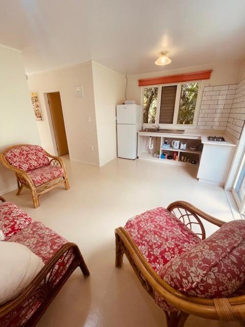 ein Wohnzimmer mit zwei Stühlen und eine Küche in der Unterkunft Mango Grove Cottage in Rarotonga