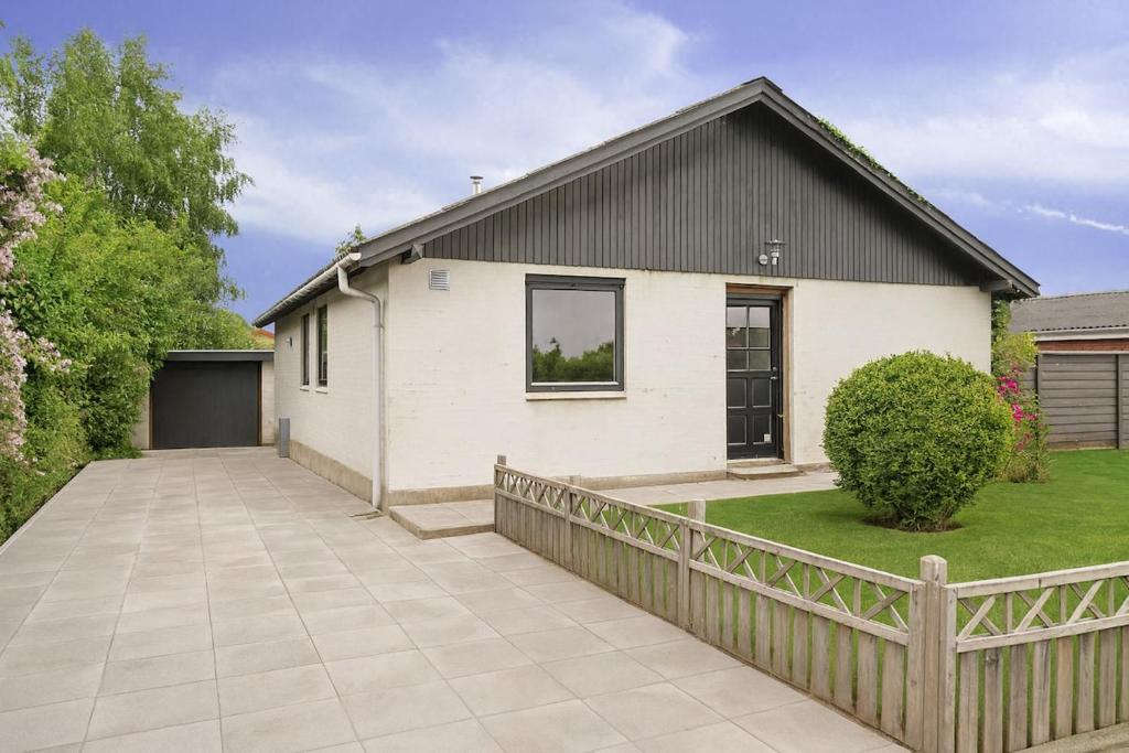 una casa blanca con techo negro y valla en The Lucky Peer - 120m2 house 4 bedroom house - full kitchen & free parking, en Odense