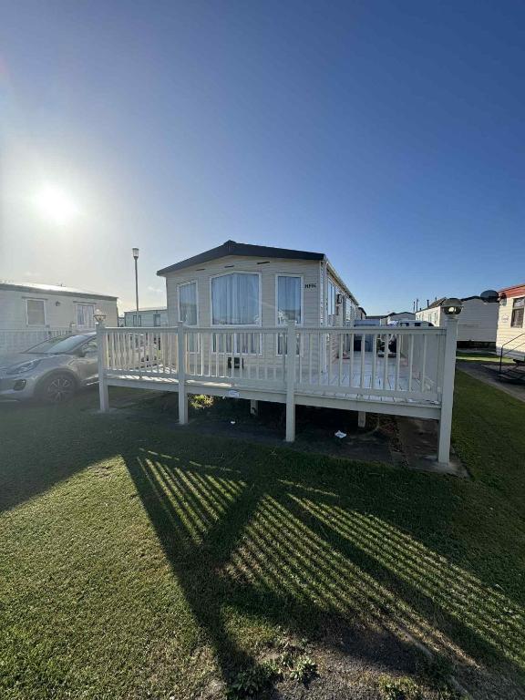 a white house with a porch and a fence at Pebble Breeze in Ingoldmells