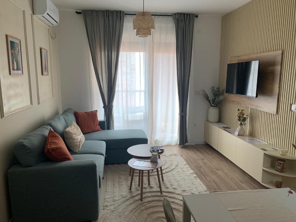 Una sala de estar con un sofá azul y una mesa. en Résidence du centre 8, en Kragujevac