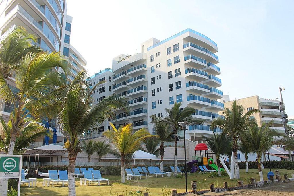 un gran edificio con sillas azules y palmeras en Cartagena Beach Front, en Cartagena de Indias