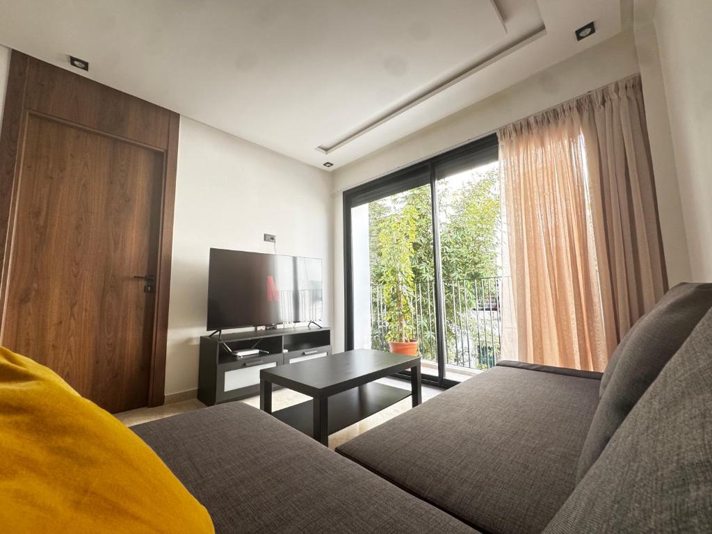 a living room with a couch and a television at Cozy green studio - Self check in, Prime location, Free parking in Casablanca