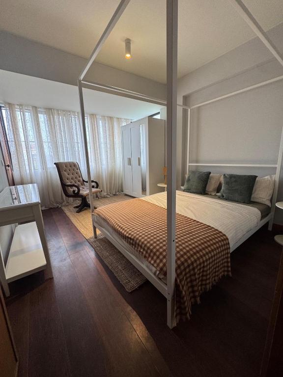 een slaapkamer met een hemelbed en een stoel bij Casa da Música Apartment in Porto