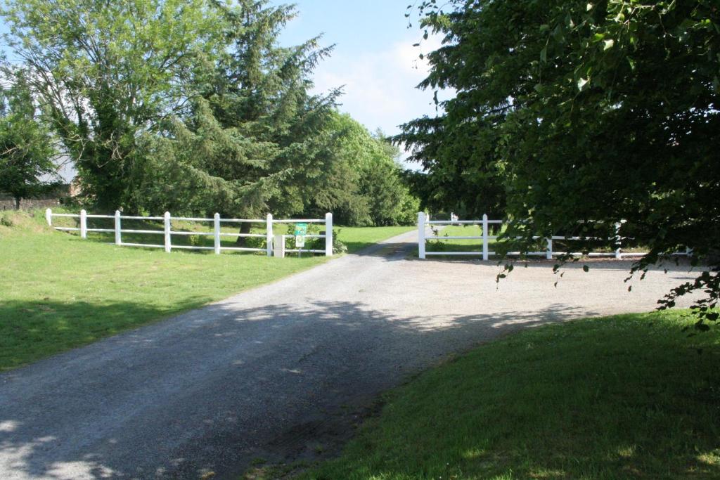 a dirt road with a white fence and trees at château de lamberville in Lamberville