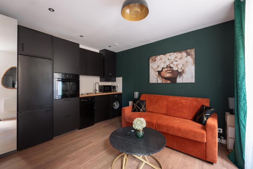a living room with a couch and a table at Studio rénové - Accès direct Paris in Montreuil