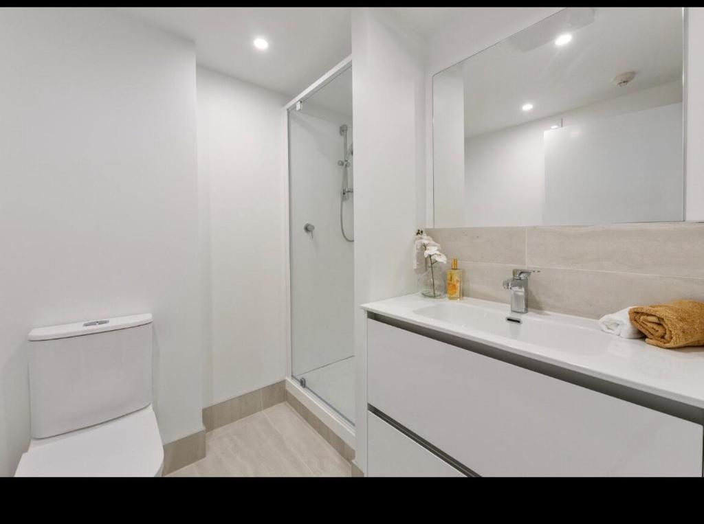 a white bathroom with a shower and a sink at Beach escape at Mount Maunganui in Mount Maunganui