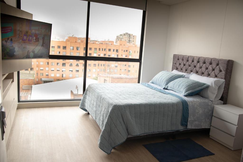 a bedroom with a bed and a large window at Corferias Embajada Usa Centro Aeropuerto Mascotas Coliving Coworking in Bogotá