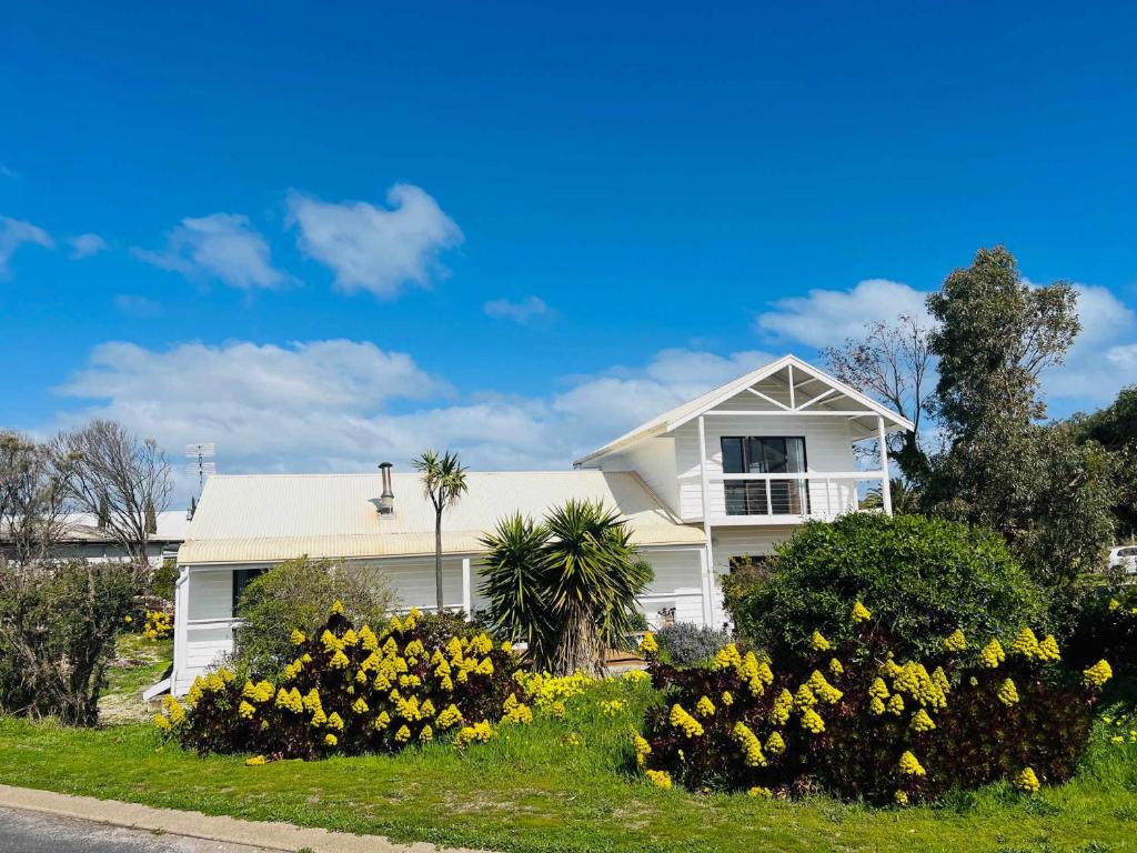 a white house with yellow flowers in front of it at The WardRobe Pet Friendly Vintage Vibes at The Seaside in Robe