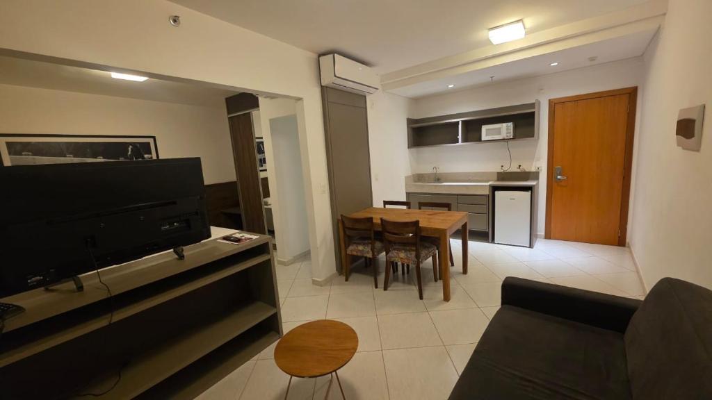 a living room and kitchen with a table and a television at Apartamento Barretos Park Hotel in Barretos