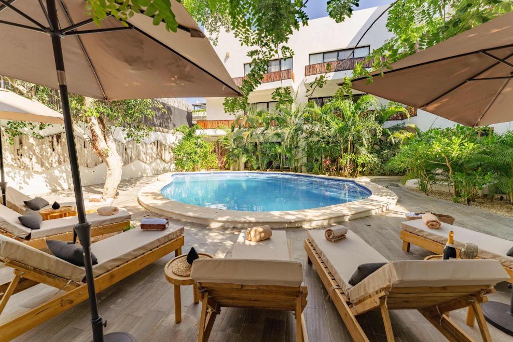 an outdoor swimming pool with chairs and an umbrella at La Veleta Hotel - Pool Access Room in Tulum