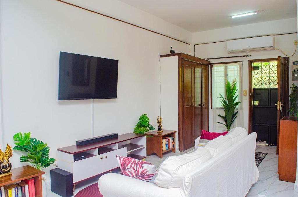 ein Wohnzimmer mit weißen Möbeln und einem Flachbild-TV in der Unterkunft Bright Diani Studio with King Bed, 2min to Beach in Diani Beach