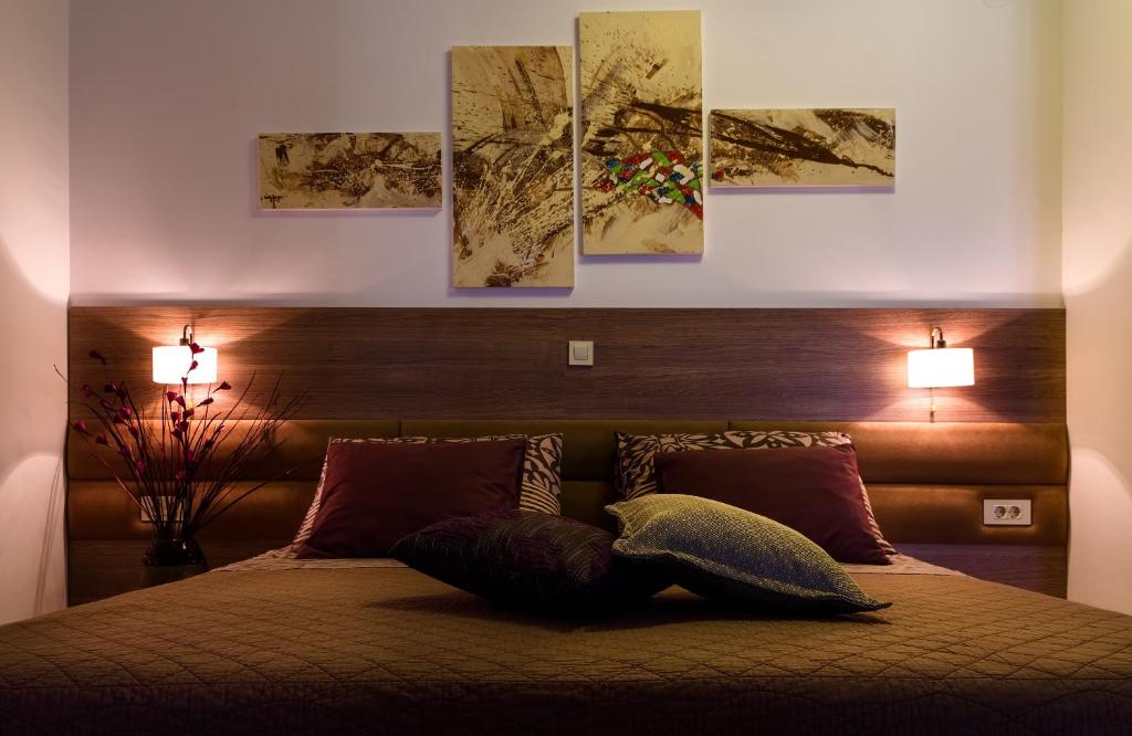 um quarto com uma cama com quatro pinturas na parede em Villa Martini - apartments & rooms em Vukovar