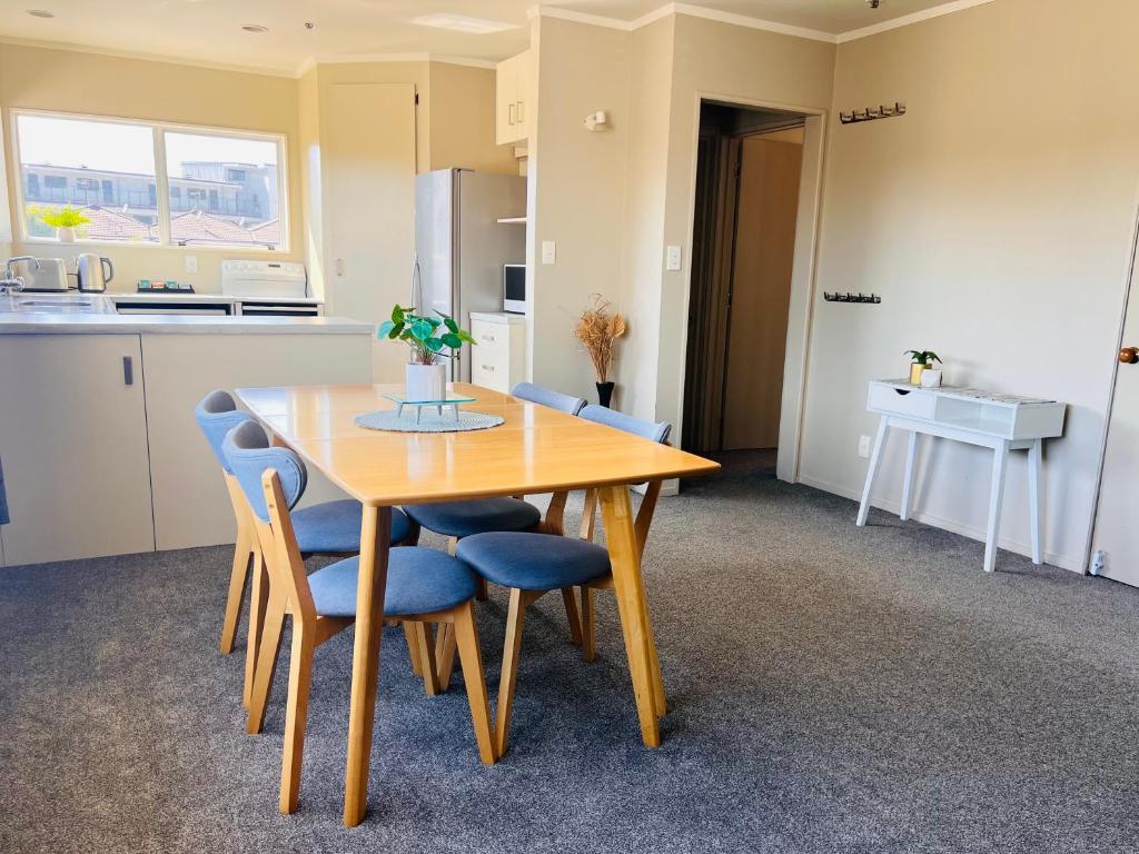a kitchen with a wooden table and blue chairs at 3 Bedroom Apartment next to Blake Park in Mount Maunganui