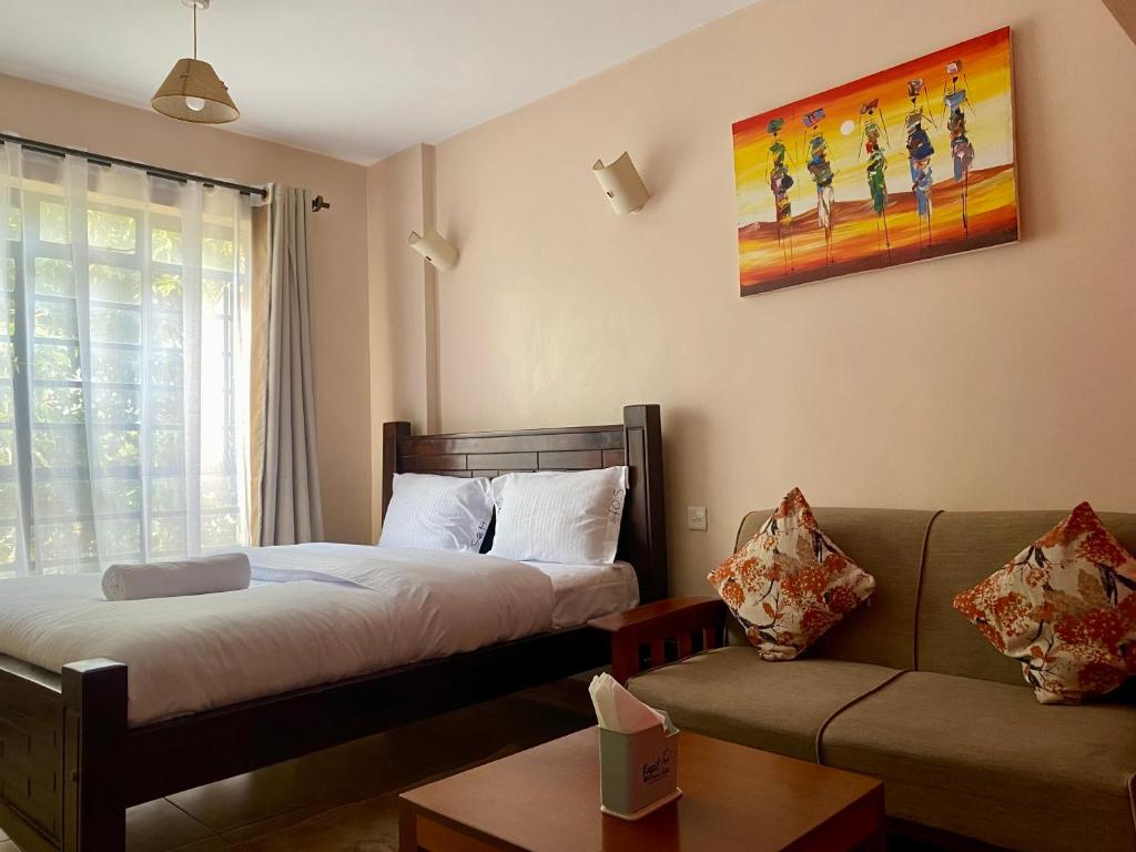 a hotel room with a bed and a couch at Furnished Studio Apartment in Nairobi West in Nairobi