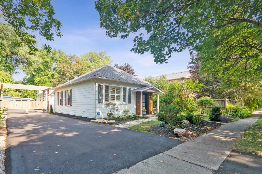 Una pequeña casa blanca con entrada para coches. en Old Town Kindergarten Vacation Home, en Niagara on the Lake