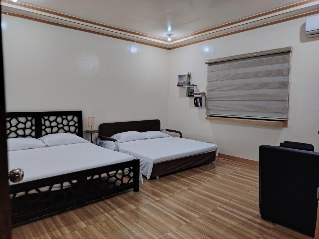 a bedroom with two beds and a window at Bon Joy Bed & Breakfast in Mabini