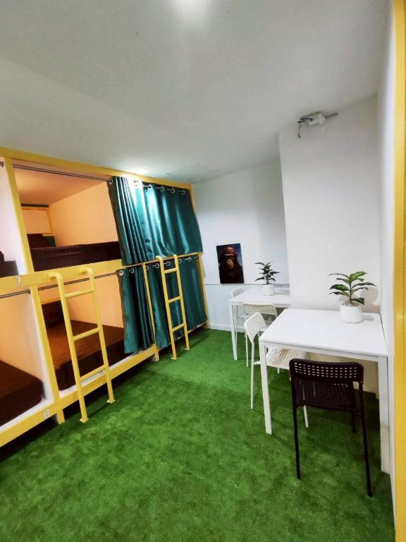 a room with two tables and a bed and green carpet at Banana Bunkhouse Hostel in Rawai Beach