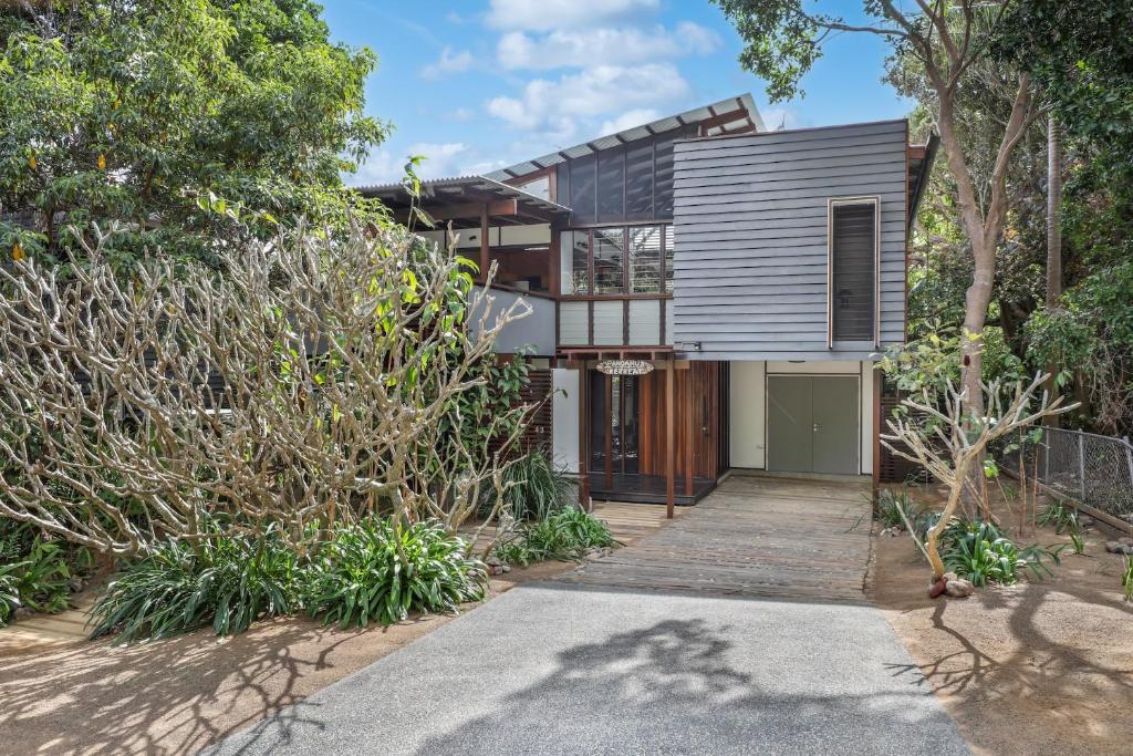 a house with a wooden door and trees at Pandanus Retreat in Point Lookout