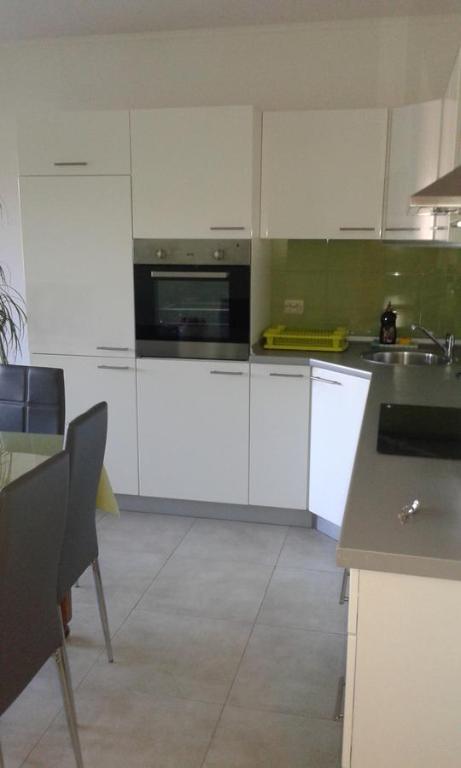 cocina con armarios blancos, fregadero y microondas en Apartment Mery, en Trogir