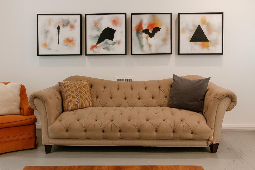 a couch in a living room with four pictures on the wall at Comfortable 6BR Getaway • WiFi • AC • Pet-Friendly in Detroit