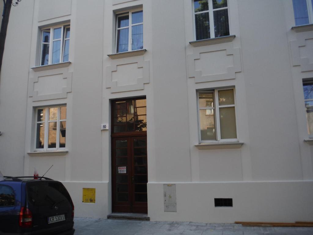 een wit gebouw met een deur en een auto voor de deur bij Kujawska 10 in Krakau