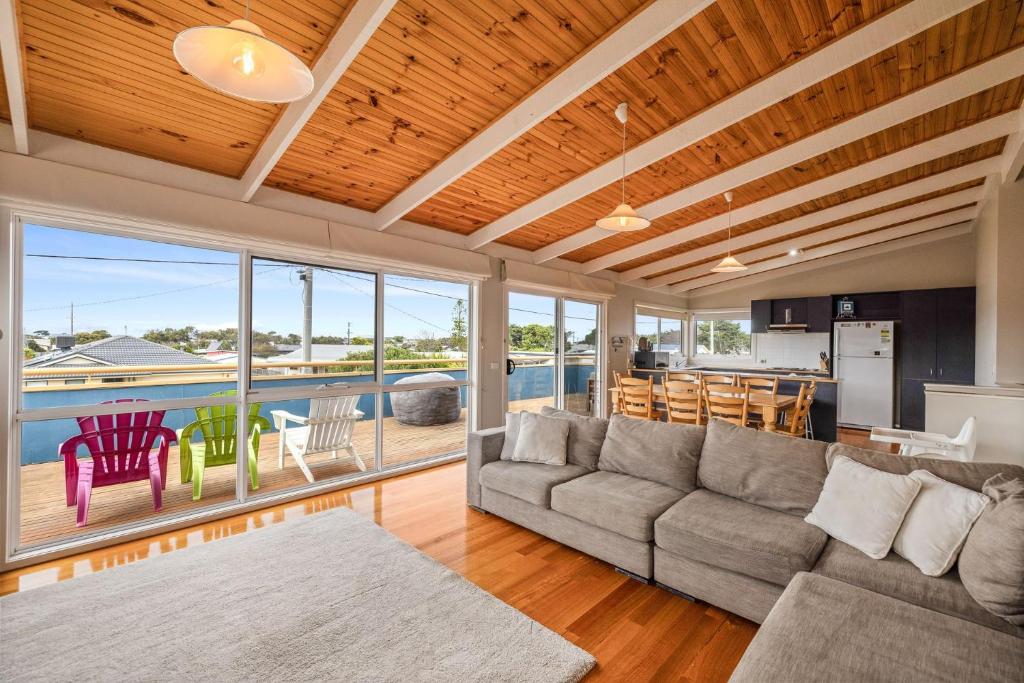 a living room with a couch and a table and chairs at Dragonfly Beach House in Sunderland Bay
