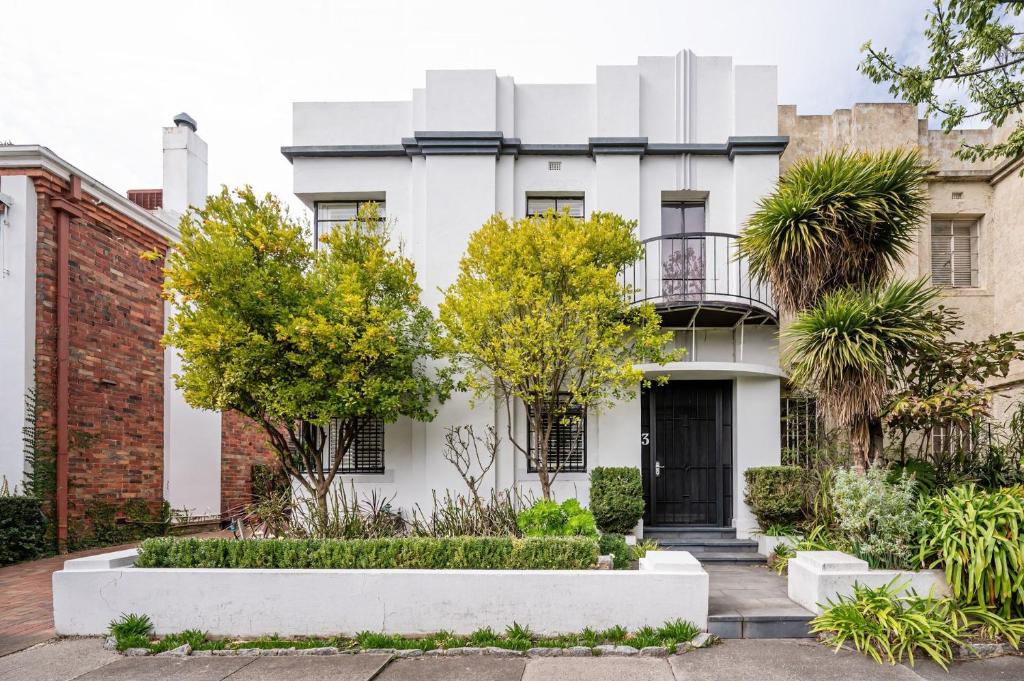 a white house with a black door and trees at Deco Days - Prahran in Melbourne