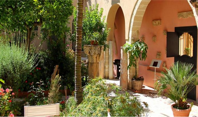 um jardim com plantas e árvores num edifício em Antica Corte delle Ninfee, Historical Private Villa em Trapani