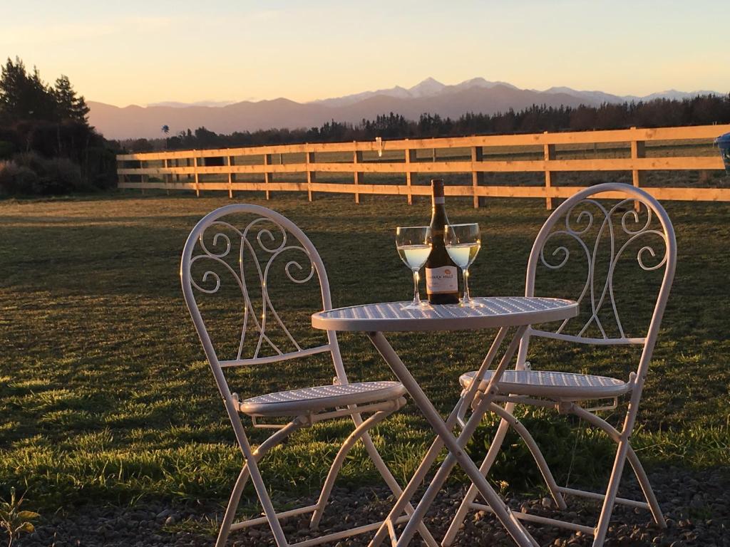 uma mesa com uma garrafa de vinho e duas cadeiras em Bentleys Country Stay em Hawarden