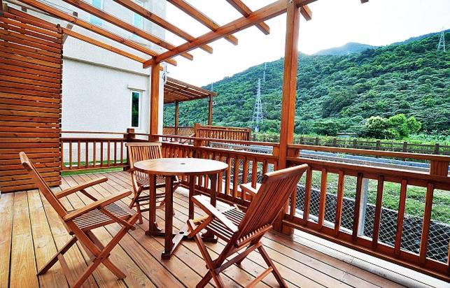 a wooden deck with a table and chairs on a balcony at Cai Feng B&amp;B in Ji&#39;an