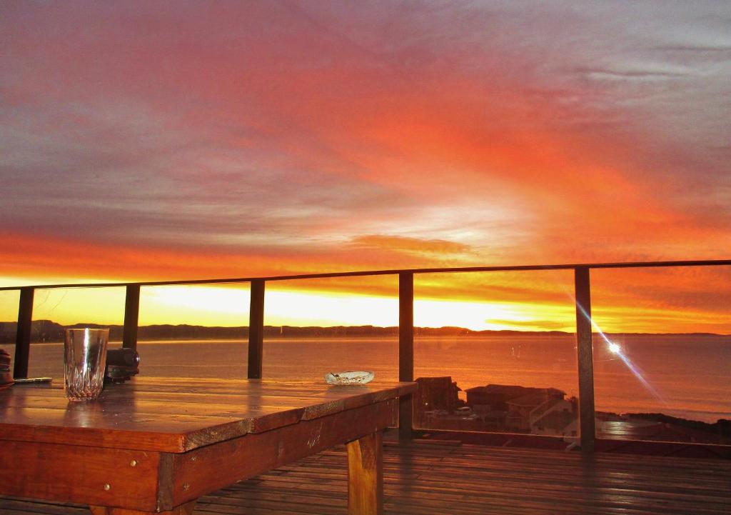 a view of a sunset from a deck with a table at Starfish Surf House in Jeffreys Bay
