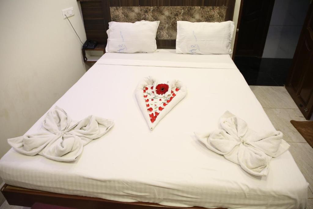 a bed with white sheets and a valentines heart at Vasantharaja Inn in Puducherry