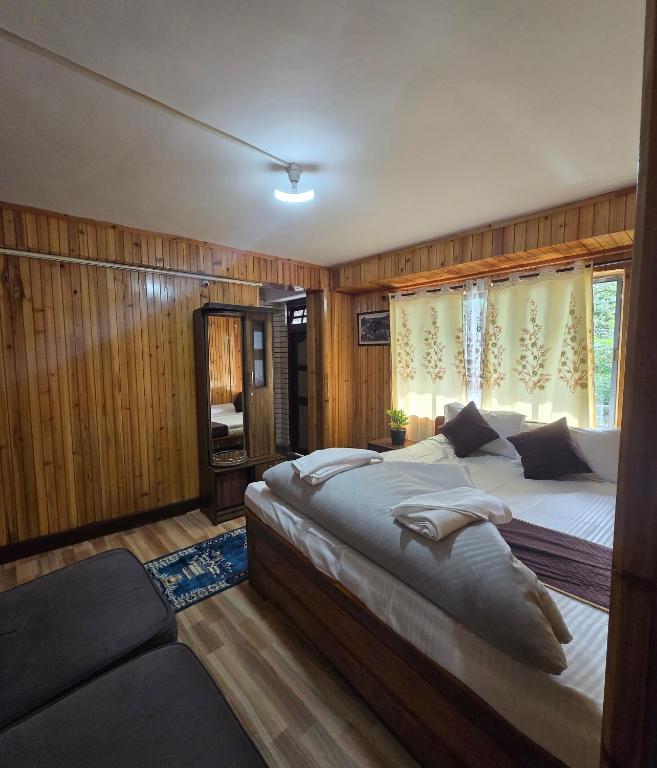 a bedroom with two beds and a large window at Zambalaas Inn in Darjeeling