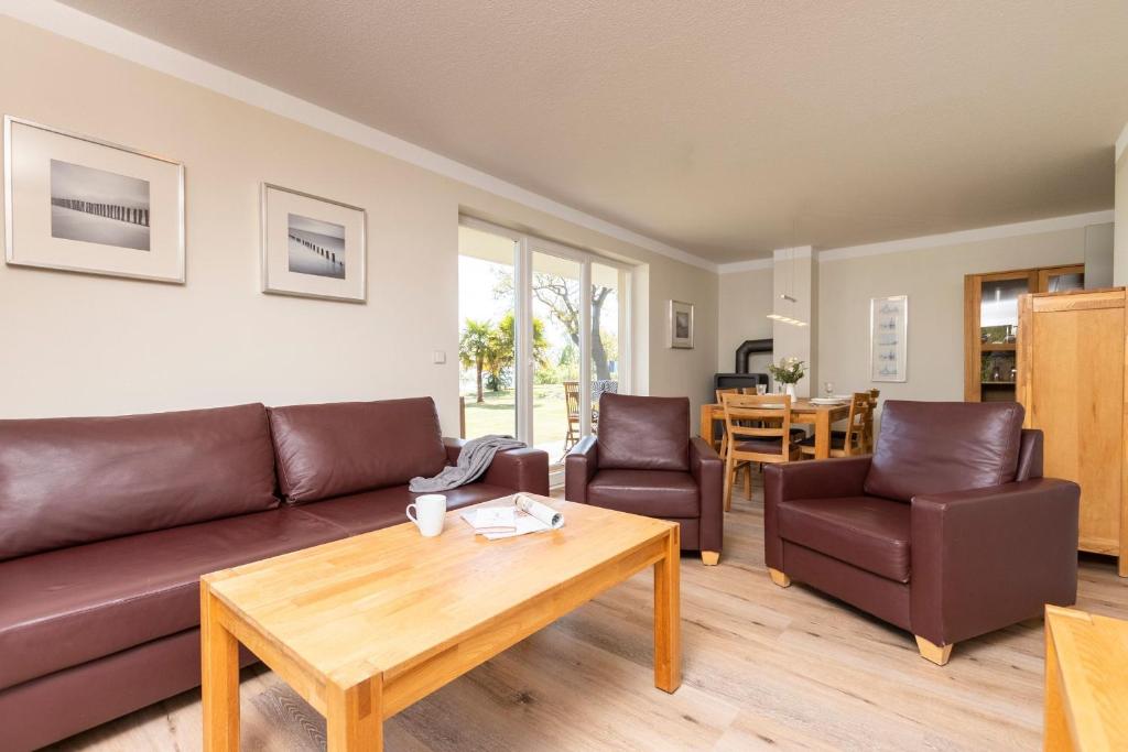 Una sala de estar con un sofá y sillas y una mesa. en FeWo Haubentaucher, en Sassnitz