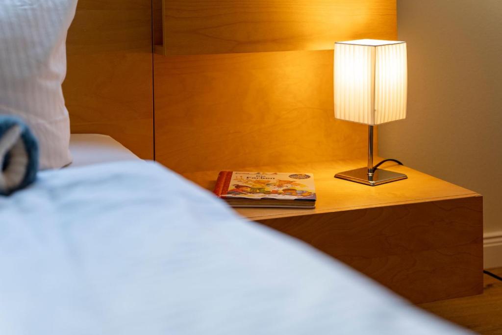 a bed with a lamp and a book on a night stand at Sassnitz - Kamin, Meerblick, Sauna, Fitness - FeWo Haubentaucher in Sassnitz