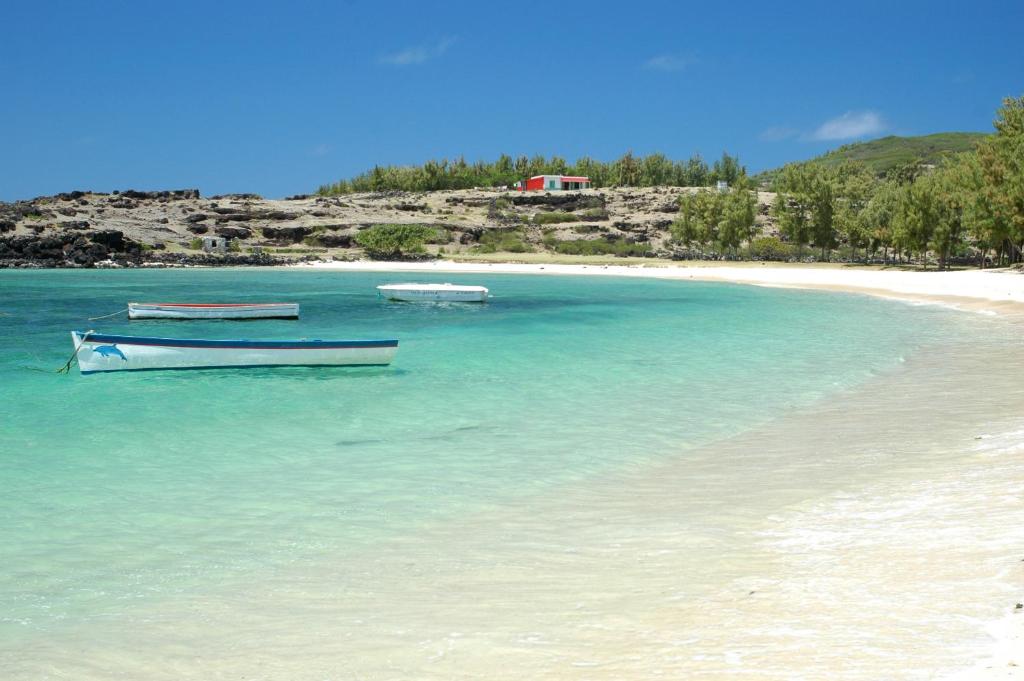 zwei Boote, die am Strand im Wasser sitzen in der Unterkunft Chez Ronald Guest House in Rodrigues Island