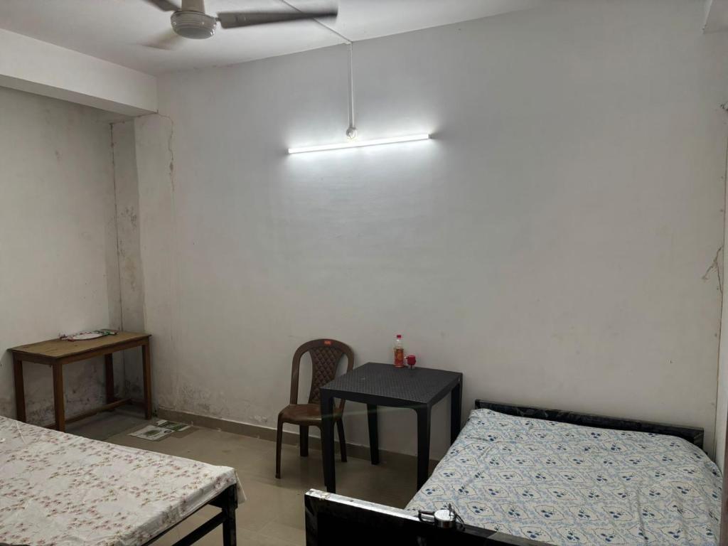 a room with two beds and a table and a ceiling fan at Mid City Homestay in Guwahati