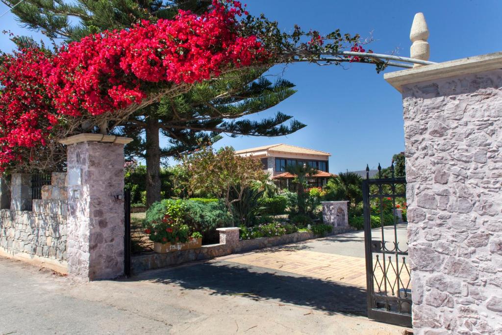 an entrance to a garden with red flowers on a gate at Villa Antikleia in Hersonissos