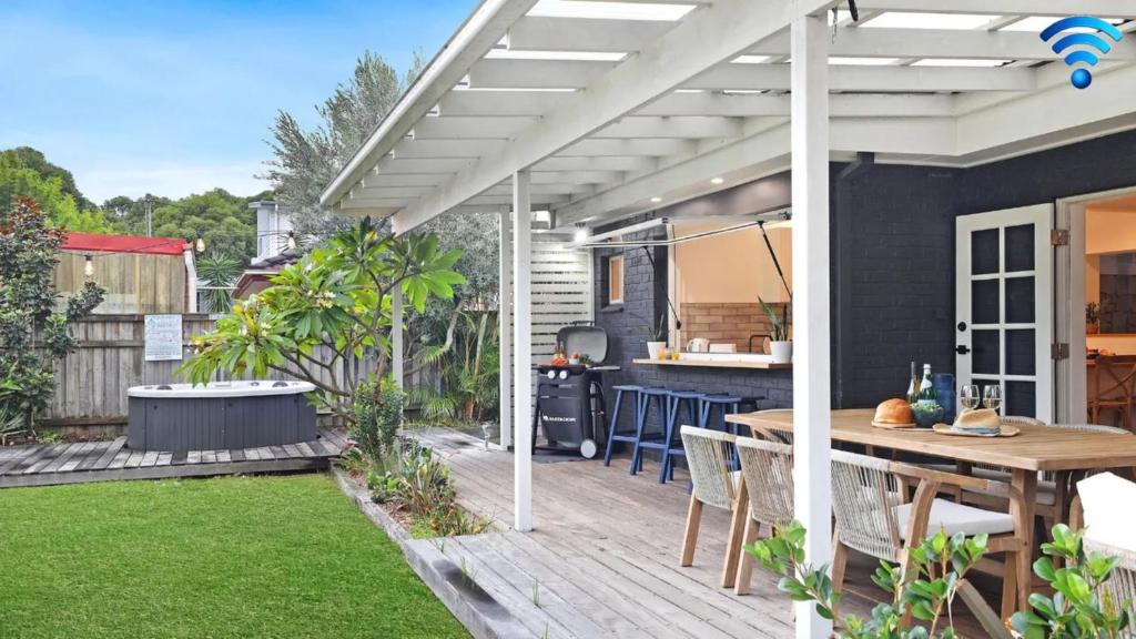 a patio with a wooden table and a white pergola at Shellhaven in Shoalhaven Heads