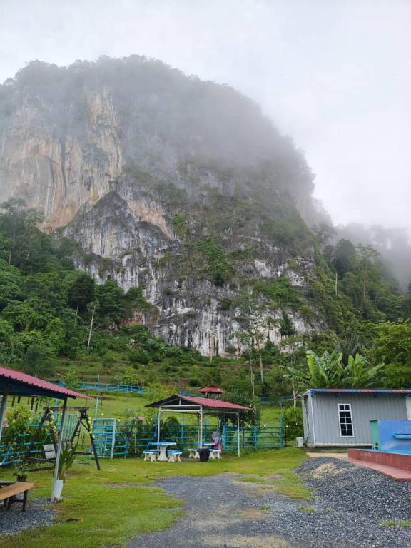 a mountain in the distance with a house and a playground at Bekbek's Village in Kangar